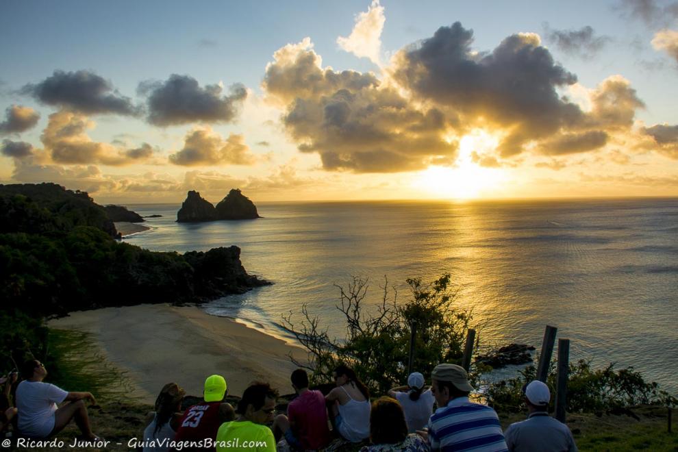 Imagem de vários turistas admirando o por do sol na direção Morro Dois Irmãos.